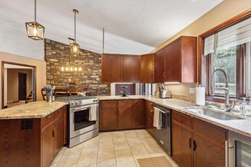 a kitchen with wooden cabinets and a stone wall at Great Group Getaway: Games Galore + Outdoor Oasis in Painesville