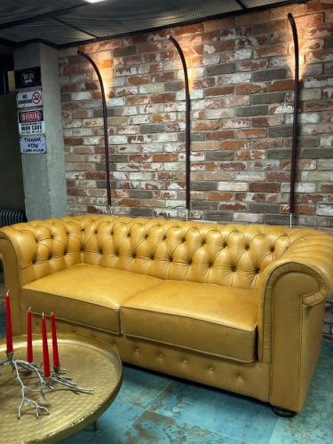 a yellow couch in a room with a brick wall at ALL - Amberstone Lux Loft in Klaipėda