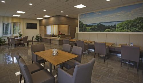 a dining room with tables and chairs and a large painting at Hotel Wittensee Schützenhof in Groß Wittensee