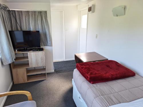 a bedroom with a bed with a red blanket on it at Picton's Waikawa Bay Holiday Park in Picton