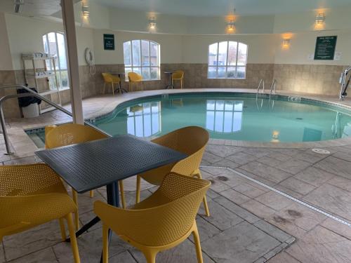 a pool with chairs and a table in front of it at La Quinta by Wyndham OKC North - Quail Springs in Oklahoma City