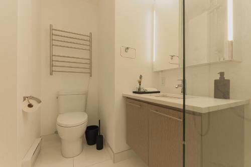 a white bathroom with a toilet and a sink at Rozenhaus Montreal Hotel in Montréal