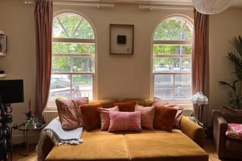 a couch sitting in a living room with two windows at Stylish & Homely 1BD Flat 1min to Clapton Sqaure! in London