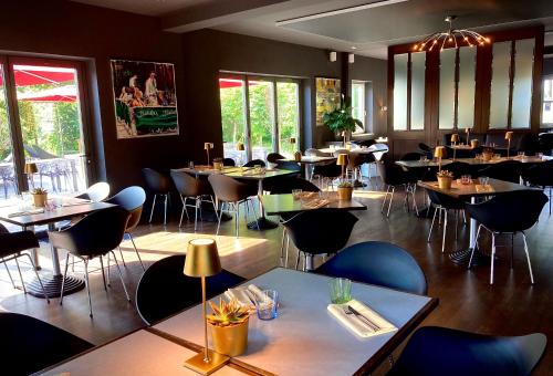 a dining room with tables and chairs and windows at Das SinGold Hotel mit Highspeed WLAN und digitalem Schlüssel in Schwabmünchen