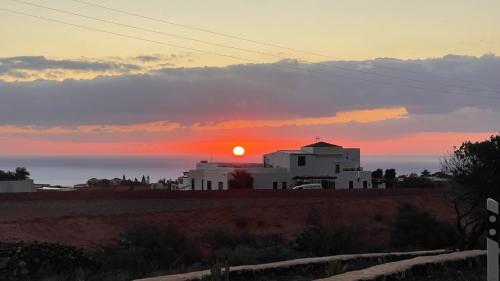 a sunset over the ocean with a white building at Can Altavista in Puerto del Rosario