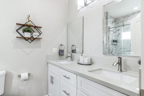 a white bathroom with two sinks and a mirror at Amazing Value with High Comfort, 14 Guests for 4BR by Disneyland, Beaches, Rodeo 39 & More in Midway City