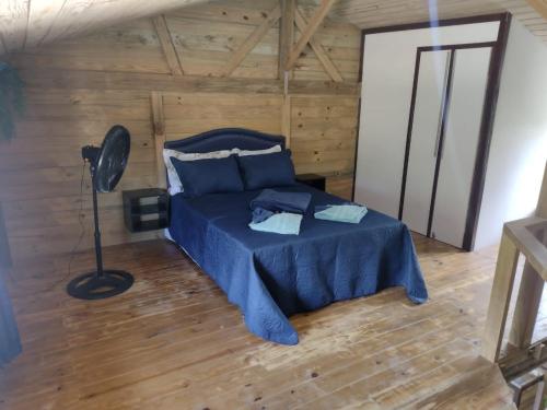 um quarto com uma cama azul num quarto de madeira em Recanto Pé da Serra em Santo Amaro da Imperatriz