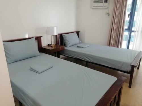 two beds sitting in a room with a window at Roxas Blvd Stunning Studio Condo Near US Embassy in Manila