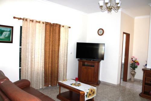 a living room with a couch and a flat screen tv at Moradia Bela House in Santa Cruz