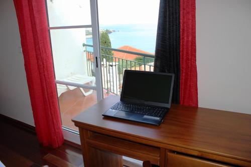 un ordenador portátil sentado en un escritorio frente a una ventana en Moradia Bela House, en Santa Cruz