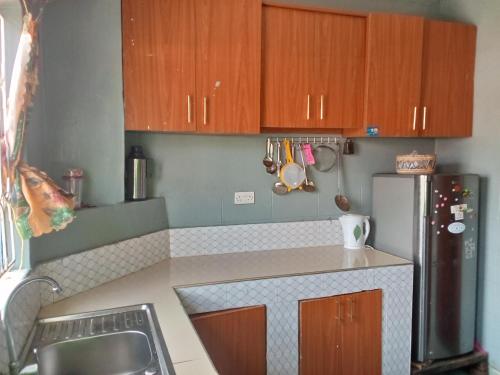 a kitchen with wooden cabinets and a refrigerator at Sam & Miriam's Homestay in Nakuru