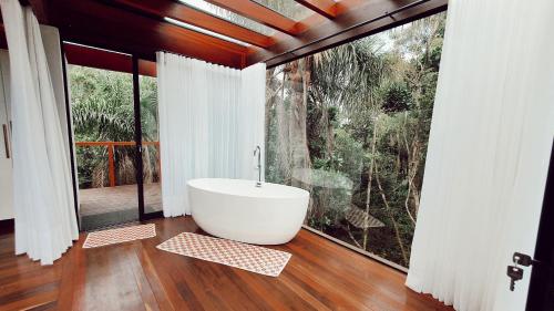 a bath tub in a room with a large window at Pousada Rosa Norte in Imbituba