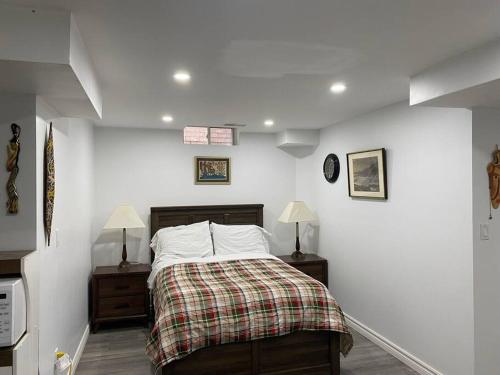 a white bedroom with a bed and two night stands at Large Separate Entrance Basement Unit 2Beds 1Washroom Sleeps 4-6 in Pickering