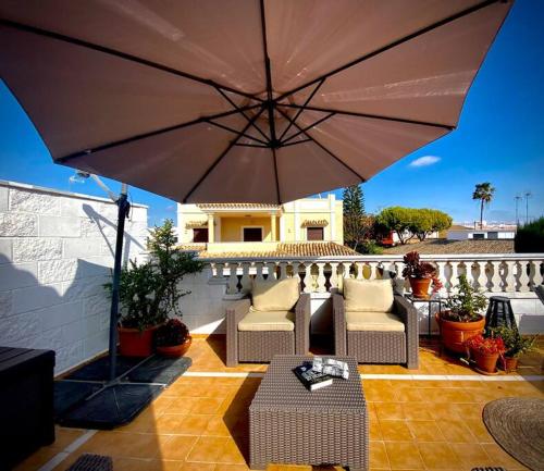 a patio with an umbrella and chairs and a table at MyChoice Villa Almadraba in Rota