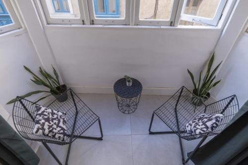 three chairs and a table in a room with windows at Green door Valletta in Valletta
