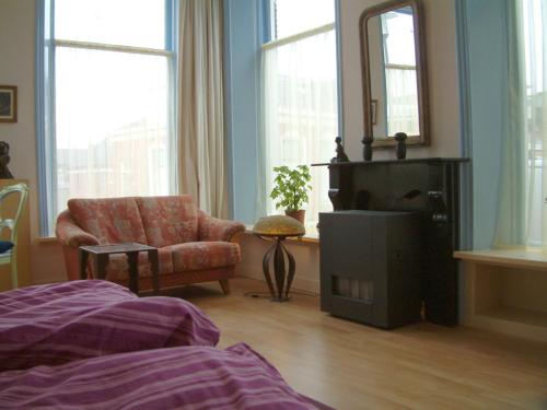 a living room with a chair and a mirror at Bij De Kunstenaars in Ulrum