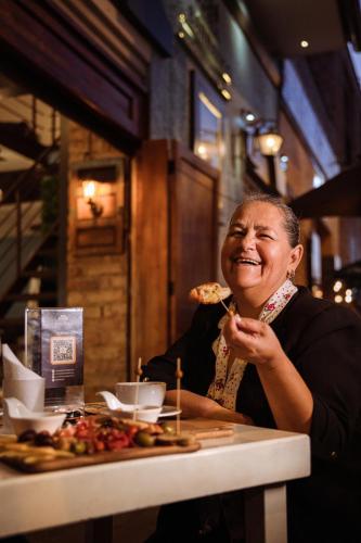 a woman sitting at a table eating a slice of pizza at Hotel Casa del Barranco in Cuenca