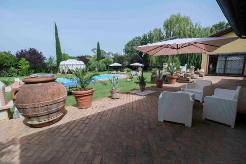 a patio with chairs and an umbrella and a pool at Villa Fiore Luxury Pool & Garden in Pisa