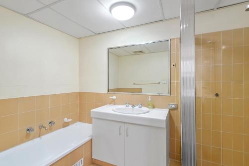 a bathroom with a sink and a tub and a mirror at Sundial 202 8-10 Hollingworth Street in Port Macquarie