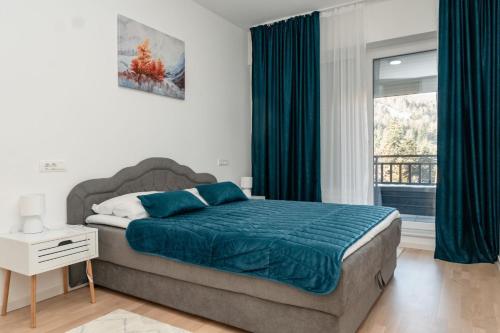 a bedroom with a bed with blue sheets and a window at HH apartments in Bjelašnica