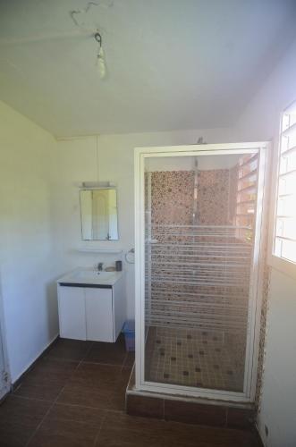 a bathroom with a glass shower with a sink at Bougain Fleuri in Deshaies