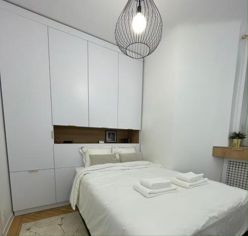 a white bedroom with a bed with white cabinets at Studio Alice Romana Square in Bucharest