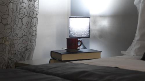 a bed with a cup and a lamp on a book at M&G holiday house in Matera
