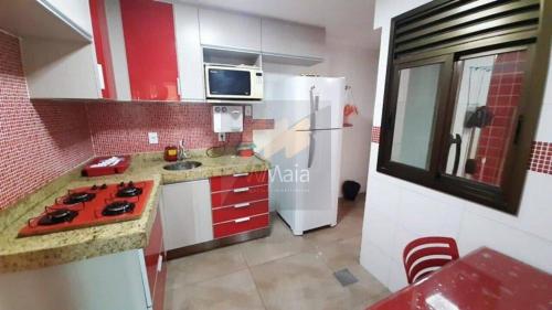 een keuken met een witte koelkast en rode kasten bij Apartamento a Duas Quadras da Praia in Cabo Frio
