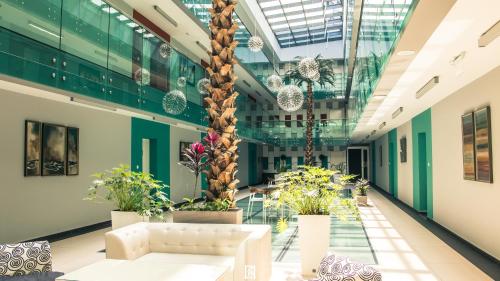 a lobby with a white couch in a building with plants at Capitоl Suites in Skopje