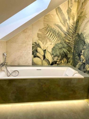 a bath tub in a bathroom with a mural at Flora & Sauna Kamieńczyk Konwaliowa 8 in Błonie