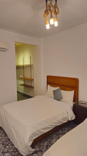 a bedroom with a large white bed and a chandelier at Alex Gate apartment - families only in Alexandria