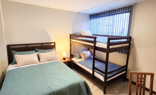 a bedroom with two bunk beds and a bed and a window at Grandioso Apartamento. in Quito