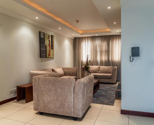uma sala de estar com dois sofás e uma televisão em Unit 14, Capella Place em East Legon