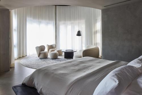 Un dormitorio con una gran cama blanca y sillas en Villa Abrazos, en San Pedro