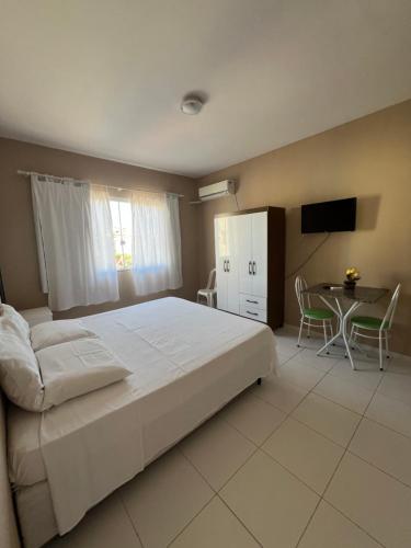 Un dormitorio con una gran cama blanca y una mesa en Residencial Água do Mar, en Florianópolis