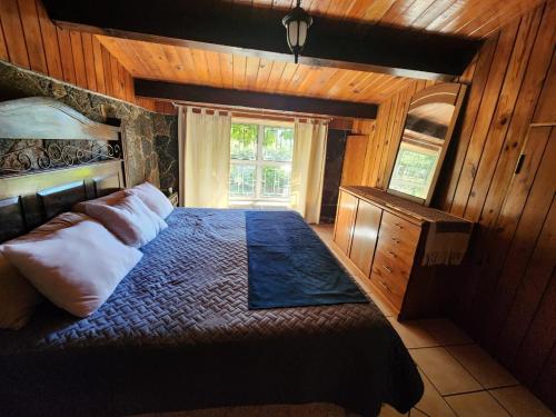 um quarto com uma cama grande num quarto com paredes de madeira em CASA XOCOMIL em Cerro de Oro