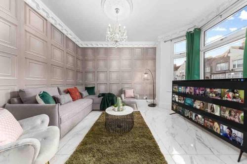 a living room with a couch and a table at Sleeps 10, CINEMA TV , 2 baths, 10 mins to Stratford in Ilford