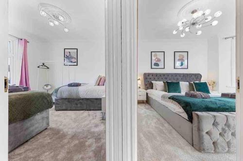 a bedroom with two beds and a mirror at Sleeps 10, CINEMA TV , 2 baths, 10 mins to Stratford in Ilford