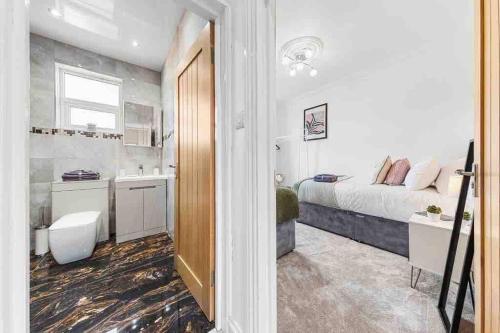 a small bedroom with a bed and a bathroom at Sleeps 10, CINEMA TV , 2 baths, 10 mins to Stratford in Ilford