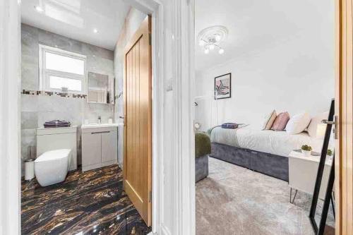 een kleine slaapkamer met een bed en een badkamer bij Sleeps 10, CINEMA TV , 2 baths, 10 mins to Stratford in Ilford