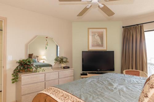 a bedroom with a tv and a large mirror at Bridgeport Condo 211 in Bradenton Beach