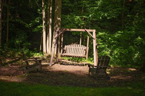 a swing and two chairs sitting in a park at The Pines Riverside Log Cabin On The Ocoee in Ocoee