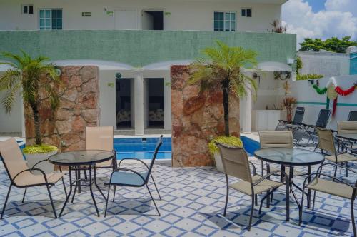 een patio met tafels en stoelen naast een zwembad bij Hotel Malecón in Campeche