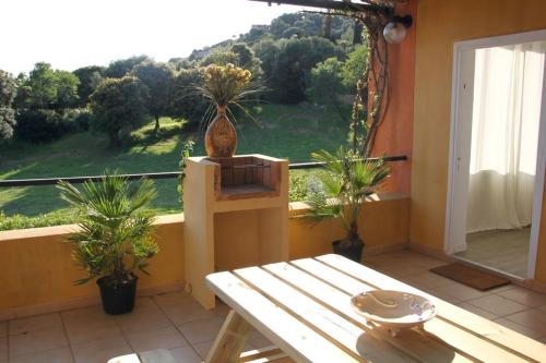 a balcony with a table and potted plants and a window at Residence Helios in Cargèse