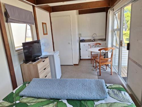 a bedroom with a bed and a kitchen with a table at Picton's Waikawa Bay Holiday Park in Picton