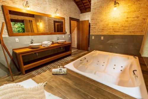 a large bathroom with a tub and a sink at Pousada Boutique Vilage de Minas in Monte Verde