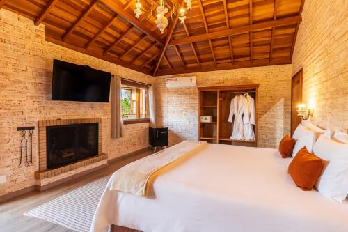 um quarto com uma cama grande e uma lareira em Pousada Boutique Vilage de Minas em Monte Verde