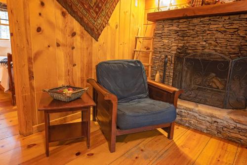 a chair in a room with a stone fireplace at The Pines Riverside Log Cabin On The Ocoee in Ocoee