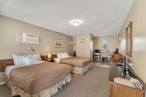 a hotel room with two beds and a flat screen tv at Badlands Motel in Drumheller