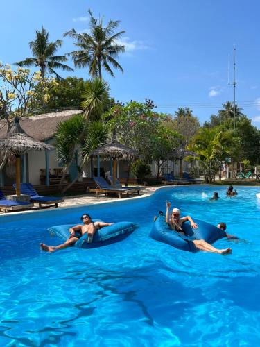 three people laying on inflatables in the water at a resort at Captain Goodtimes in Gili Islands
